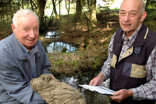 Reinhold Cronau und Willy Becker mit einem fertigen B&uuml;ndel Flachsgarn im Wald an den wassergef&uuml;llten Flachsl&ouml;chern